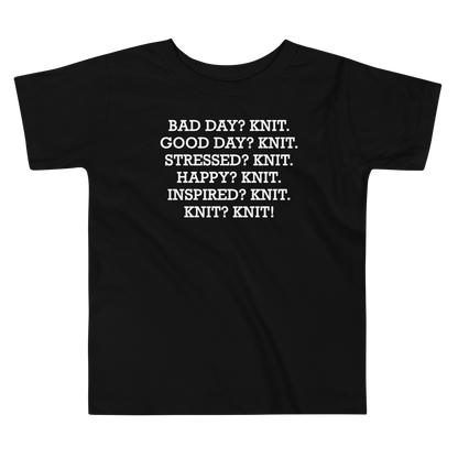 "Bad Day? Knit. Good Day? Knit. Stressed? Knit. Happy? Knit. Inspired? Knit. Knit? Knit!" printed on a black toddler short sleeve tee laying on a flat surface