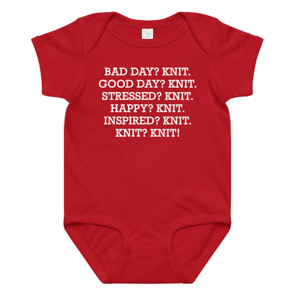 "Bad Day? Knit. Good Day? Knit. Stressed? Knit. Happy? Knit. Inspired? Knit. Knit? Knit!" printed on a red baby jersey bodysuit laying on a flat surface amongst other clothes