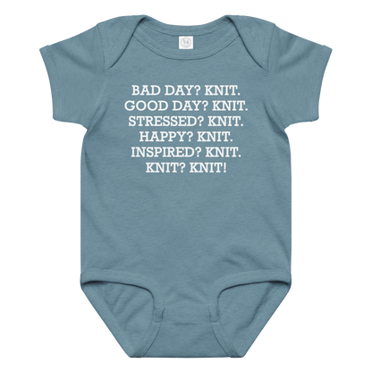 "Bad Day? Knit. Good Day? Knit. Stressed? Knit. Happy? Knit. Inspired? Knit. Knit? Knit!" printed on a vintage indigo baby jersey bodysuit laying on a flat surface amongst other clothes