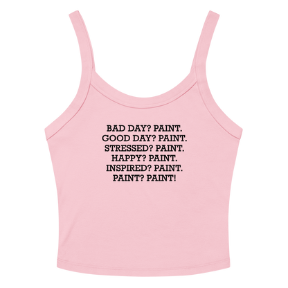"Bad Day? Paint. Good Day? Paint. Stressed? Paint. Happy? Paint. Inspired? Paint. Paint? Paint!" printed on a solid pink blend women's micro-rib tanktop laying on a flat surface amongst sunglasses and shorts
