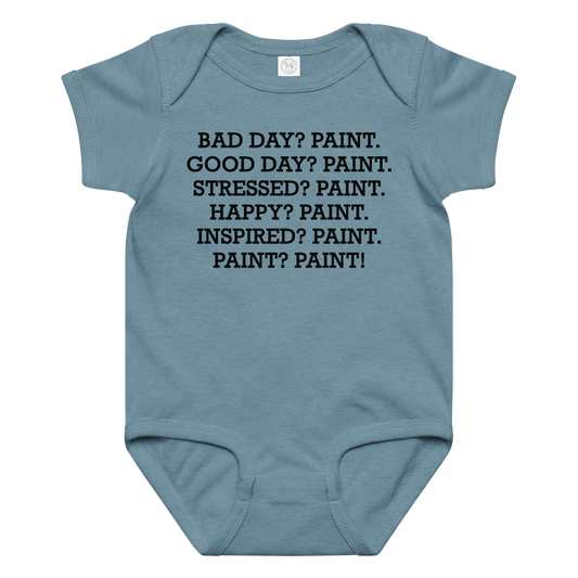 "Bad Day? Paint. Good Day? Paint. Stressed? Paint. Happy? Paint. Inspired? Paint. Paint? Paint!" printed on a vintage indigo baby jersey bodysuit laying on a flat surface amongst other clothes