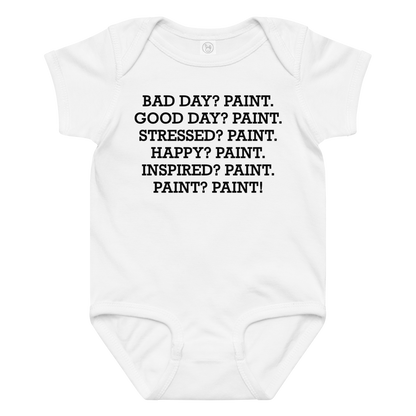 "Bad Day? Paint. Good Day? Paint. Stressed? Paint. Happy? Paint. Inspired? Paint. Paint? Paint!" printed on a white baby jersey bodysuit laying on a flat surface amongst other clothes