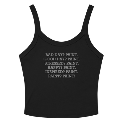 "Bad Day? Paint. Good Day? Paint. Stressed? Paint. Happy? Paint. Inspired? Paint. Paint? Paint!" printed on a solid black blend women's micro-rib tanktop laying on a flat surface amongst sunglasses and shorts