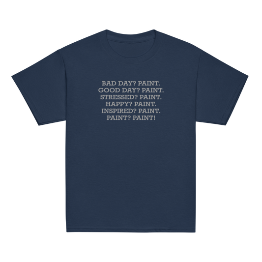 "Bad Day? Paint. Good Day? Paint. Stressed? Paint. Happy? Paint. Inspired? Paint. Paint? Paint!" printed on a navy youth classic tee laying on a flat surface