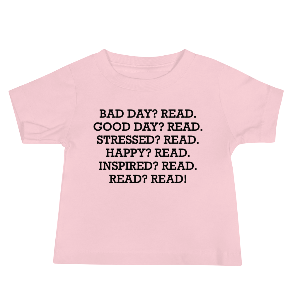 "Bad Day? Read. Good Day? Read. Stressed? Read. Happy? Read. Inspired? Read. Read? Read!" printed on a pink baby jersey short sleeve tee laying on a flat surface