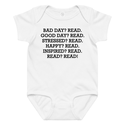 "Bad Day? Read. Good Day? Read. Stressed? Read. Happy? Read. Inspired? Read. Read? Read!" printed on a white baby jersey bodysuit laying on a flat surface amongst other clothes