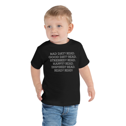 "Bad Day? Read. Good Day? Read. Stressed? Read. Happy? Read. Inspired? Read. Read? Read!" printed on a black toddler short sleeve tee worn by a male