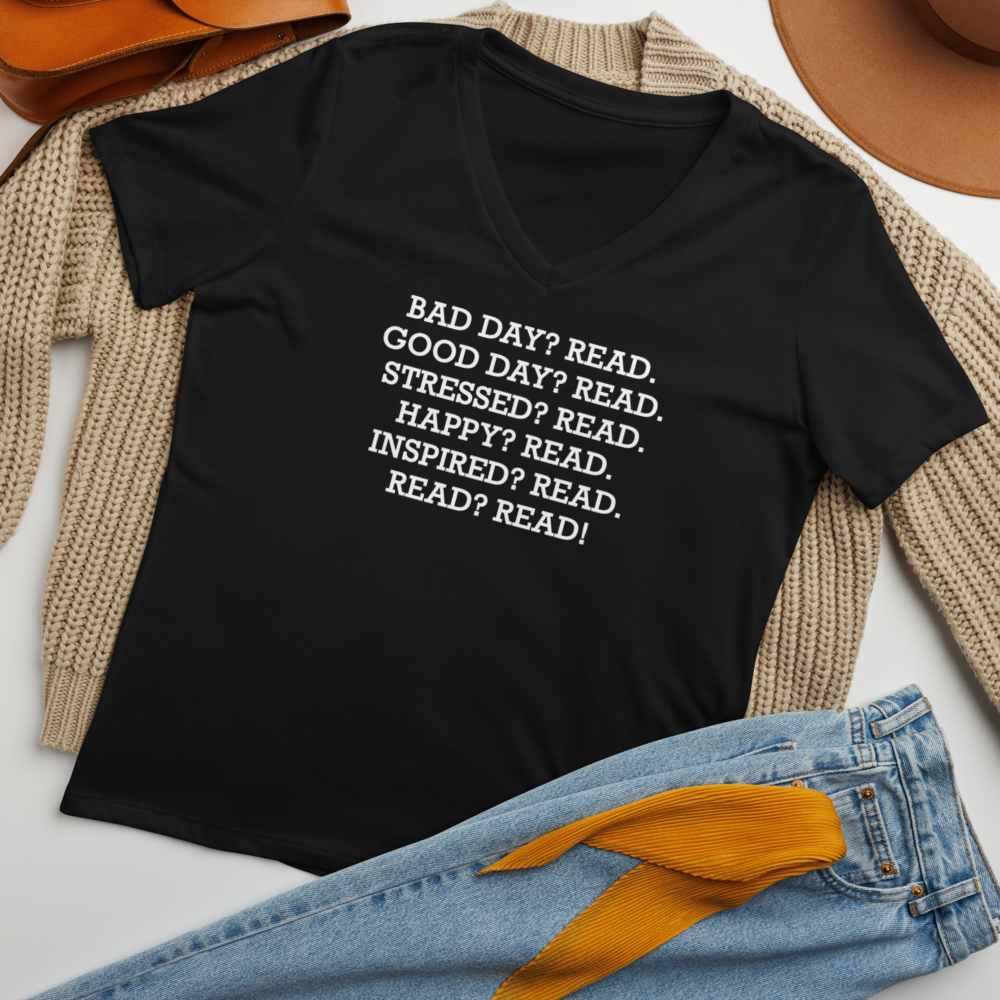 "Bad Day? Read. Good Day? Read. Stressed? Read. Happy? Read. Inspired? Read. Read? Read!" printed on a solid black blend women's relaxed v-neck t-shirt laying on a flat surface amongst other clothes