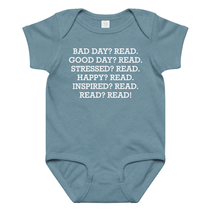 "Bad Day? Read. Good Day? Read. Stressed? Read. Happy? Read. Inspired? Read. Read? Read!" printed on a vintage indigo baby jersey bodysuit laying on a flat surface amongst other clothes
