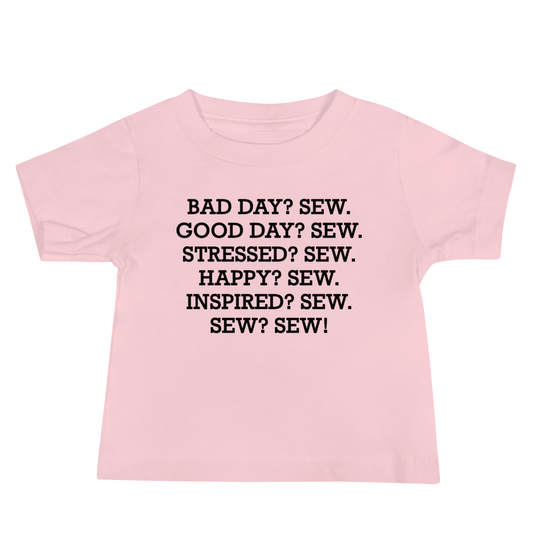 "Bad Day? Sew. Good Day? Sew. Stressed? Sew. Happy? Sew. Inspired? Sew. Sew? Sew!" printed on a pink baby jersey short sleeve tee laying on a flat surface