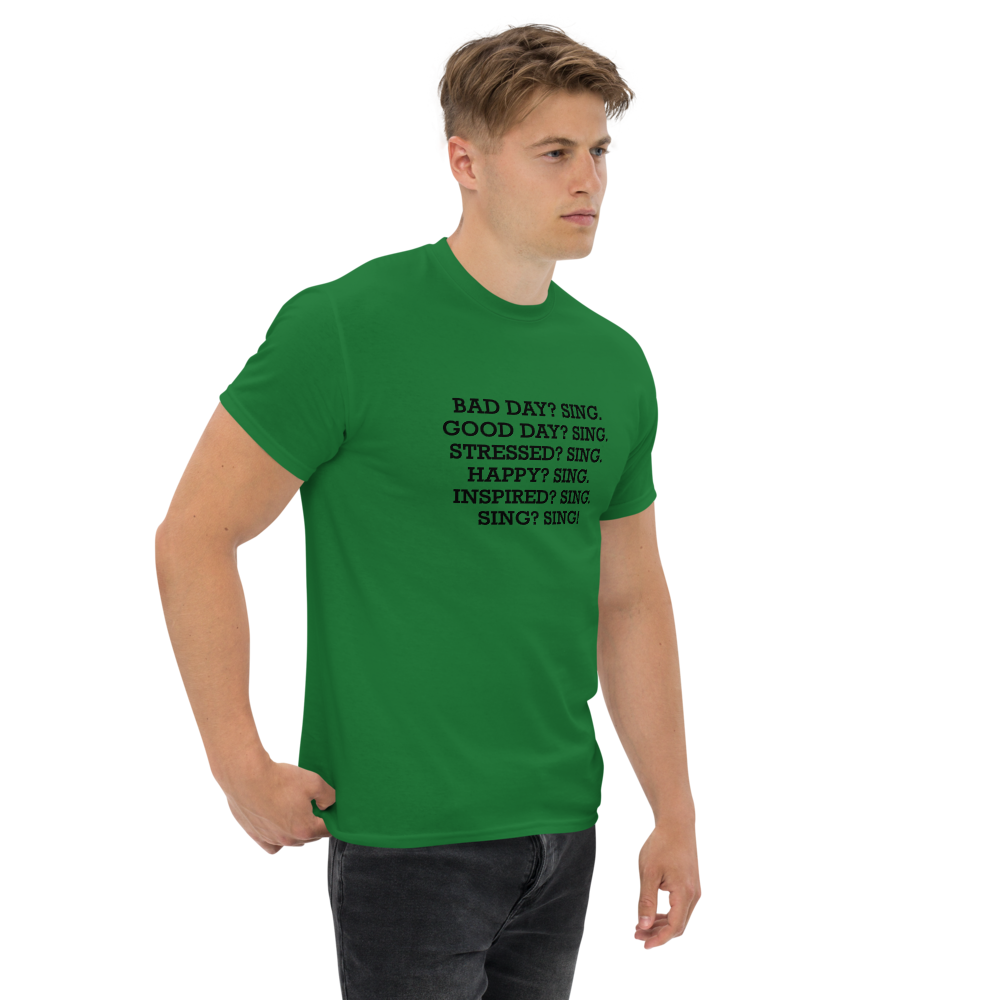 "Bad Day? Sing. Good Day? Sing. Stressed? Sing. Happy? Sing. Inspired? Sing. Sing? Sing!" printed on a turf green unisex classic tee worn by a male