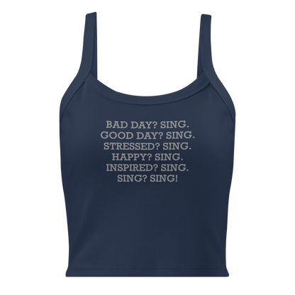 "Bad Day? Sing. Good Day? Sing. Stressed? Sing. Happy? Sing. Inspired? Sing. Sing? Sing!" printed on a solid navy blend women's micro-rib tanktop laying on a flat surface