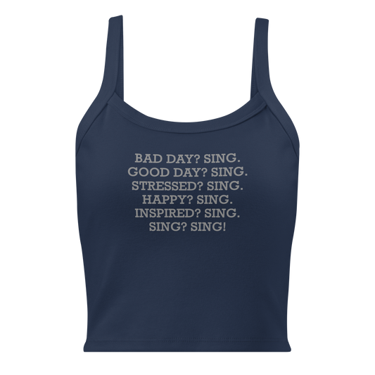 "Bad Day? Sing. Good Day? Sing. Stressed? Sing. Happy? Sing. Inspired? Sing. Sing? Sing!" printed on a solid navy blend women's micro-rib tanktop laying on a flat surface