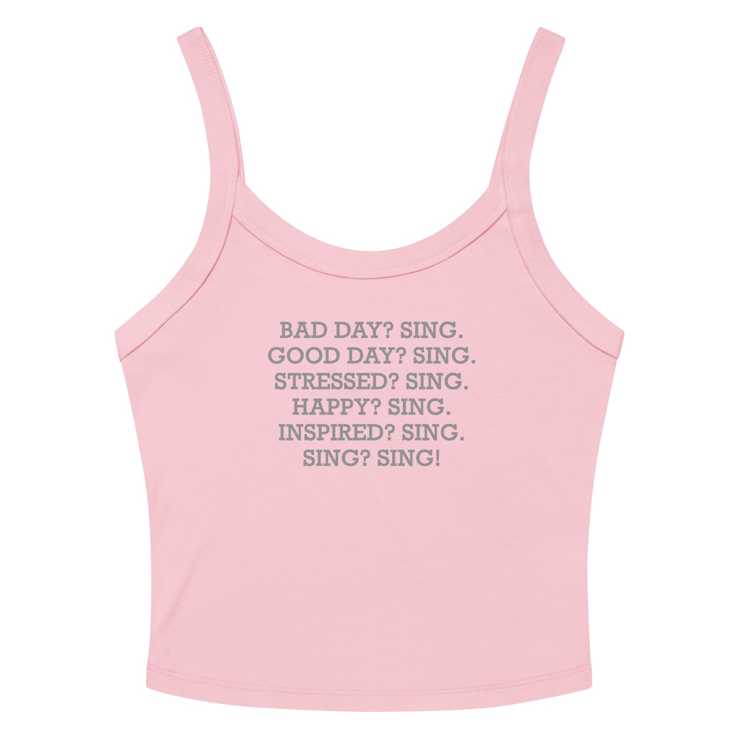 "Bad Day? Sing. Good Day? Sing. Stressed? Sing. Happy? Sing. Inspired? Sing. Sing? Sing!" printed on a solid pink blend women's micro-rib tanktop laying on a flat surface amongst sunglasses and shorts