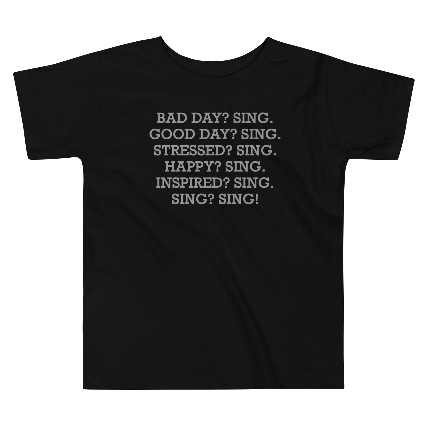 "Bad Day? Sing. Good Day? Sing. Stressed? Sing. Happy? Sing. Inspired? Sing. Sing? Sing!" printed on a black toddler short sleeve tee laying on a flat surface