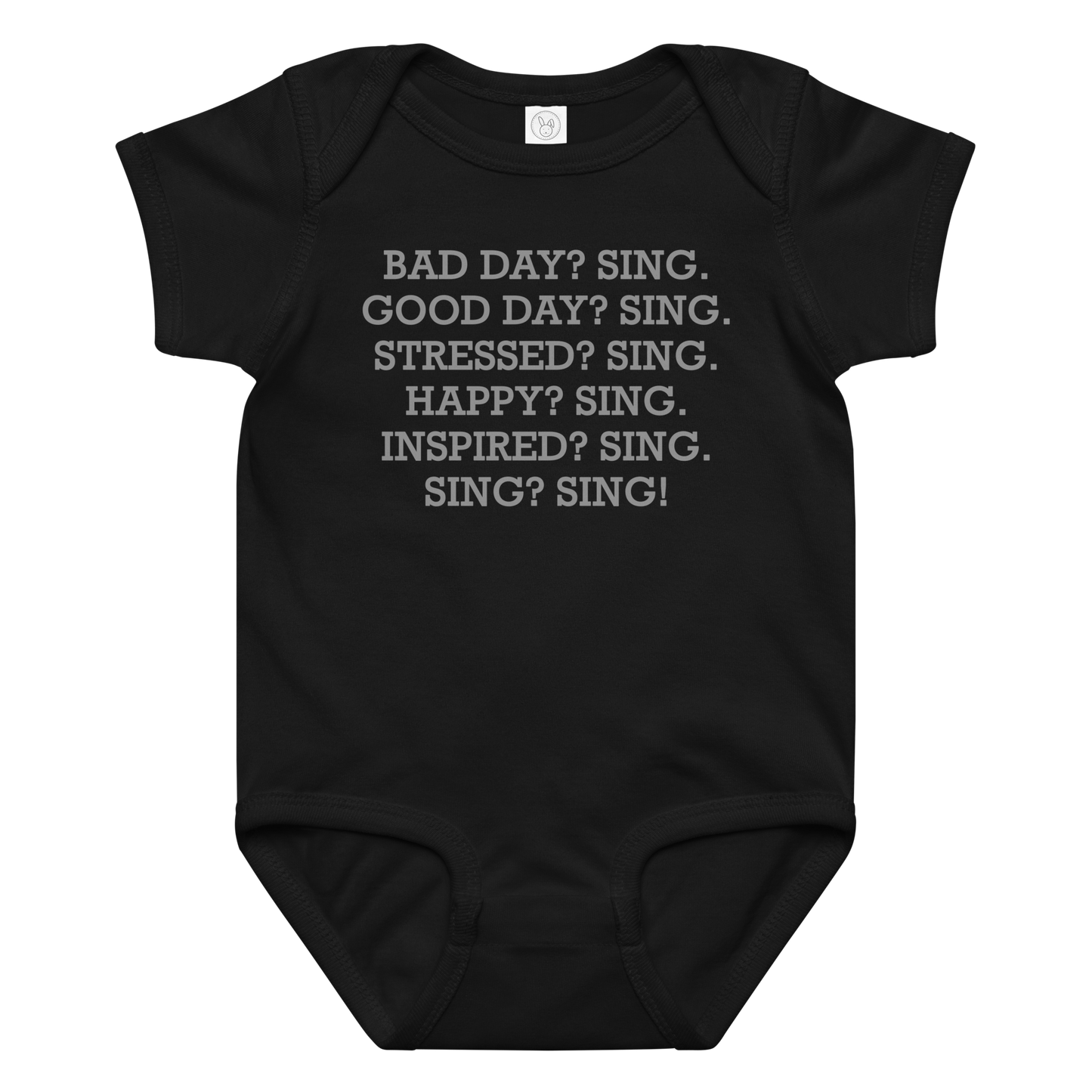 "Bad Day? Sing. Good Day? Sing. Stressed? Sing. Happy? Sing. Inspired? Sing. Sing? Sing!" printed on a black baby jersey bodysuit laying on a flat surface amongst other clothes
