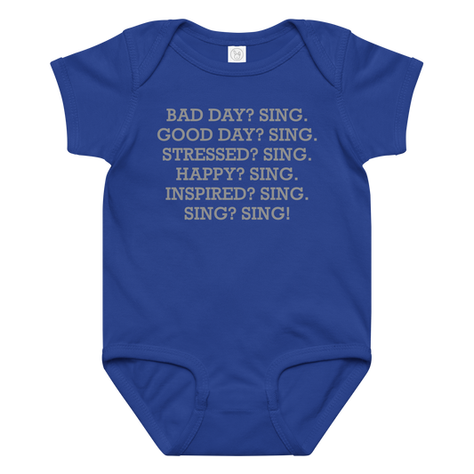 "Bad Day? Sing. Good Day? Sing. Stressed? Sing. Happy? Sing. Inspired? Sing. Sing? Sing!" printed on a royal baby jersey bodysuit laying on a flat surface amongst other clothes