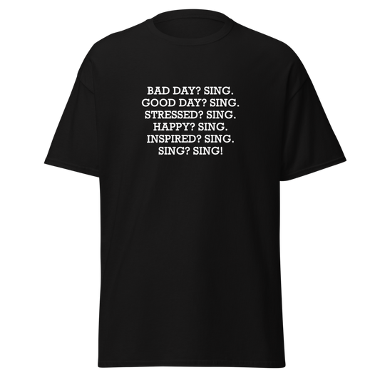 "Bad Day? Sing. Good Day? Sing. Stressed? Sing. Happy? Sing. Inspired? Sing. Sing? Sing!" printed on a black unisex classic tee laying on a flat surface