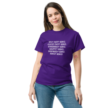 "Bad Day? Sing. Good Day? Sing. Stressed? Sing. Happy? Sing. Inspired? Sing. Sing? Sing!" printed on a purple unisex classic tee worn by a female