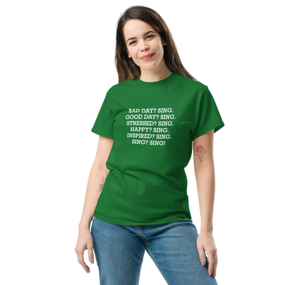 "Bad Day? Sing. Good Day? Sing. Stressed? Sing. Happy? Sing. Inspired? Sing. Sing? Sing!" printed on a turf green unisex classic tee worn by a female