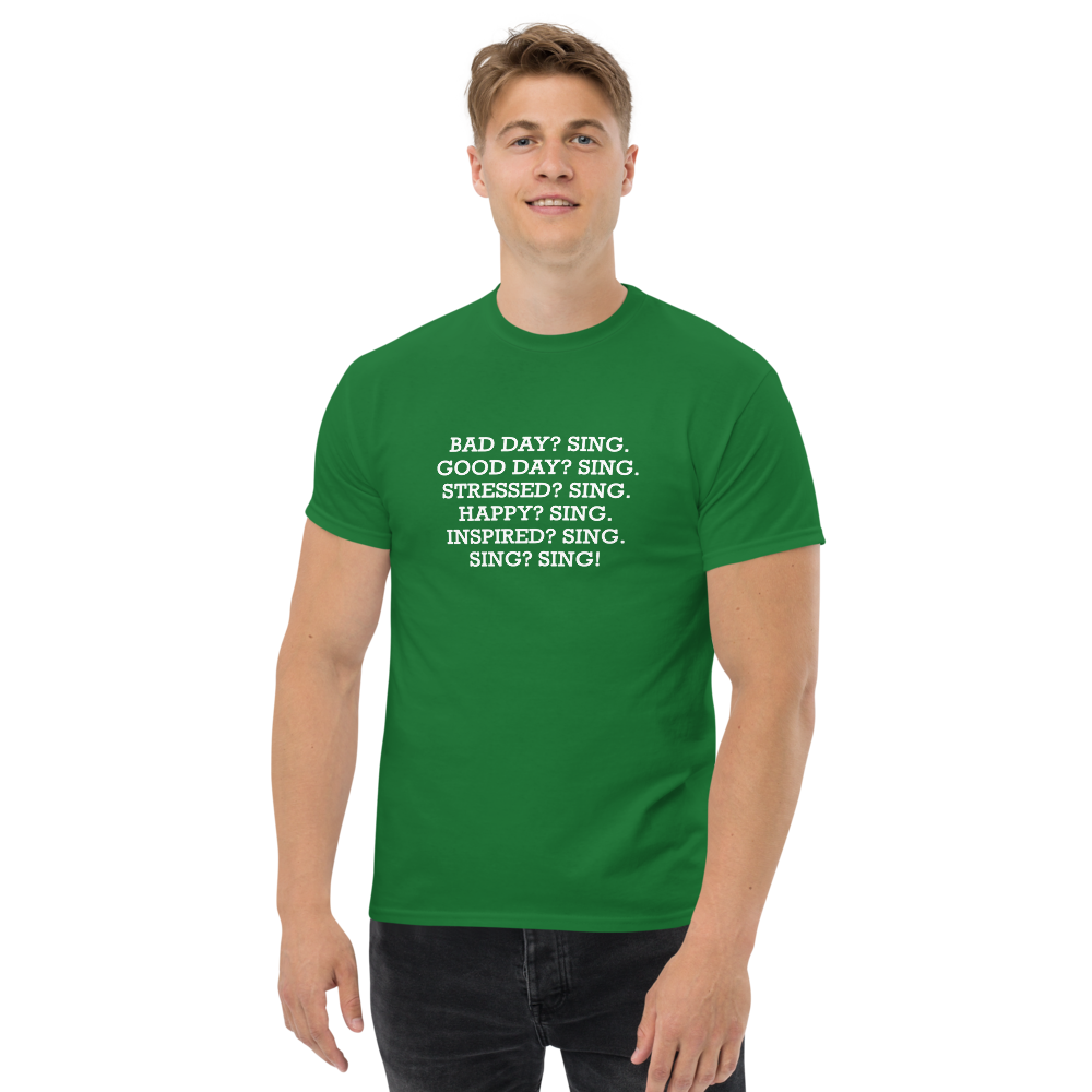 "Bad Day? Sing. Good Day? Sing. Stressed? Sing. Happy? Sing. Inspired? Sing. Sing? Sing!" printed on a turf green unisex classic tee worn by a male