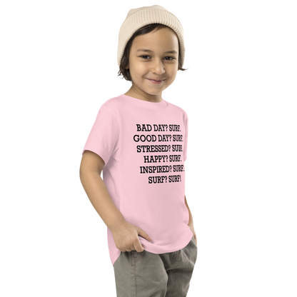 "Bad Day? Surf. Good Day? Surf. Stressed? Surf. Happy? Surf. Inspired? Surf. Surf? Surf!" printed on a pink toddler short sleeve tee worn by a male who is also wearing a knit cap