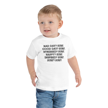 "Bad Day? Surf. Good Day? Surf. Stressed? Surf. Happy? Surf. Inspired? Surf. Surf? Surf!" printed on a white toddler short sleeve tee worn by a male