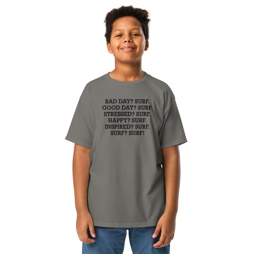 "Bad Day? Surf. Good Day? Surf. Stressed? Surf. Happy? Surf. Inspired? Surf. Surf? Surf!" printed on a charcoal youth classic tee worn by a male