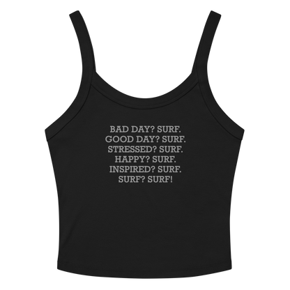 "Bad Day? Surf. Good Day? Surf. Stressed? Surf. Happy? Surf. Inspired? Surf. Surf? Surf!" printed on a solid black blend women's micro-rib tanktop laying on a flat surface amongst sunglasses and shorts
