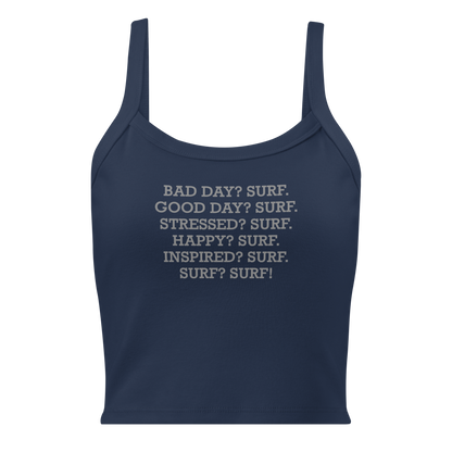 "Bad Day? Surf. Good Day? Surf. Stressed? Surf. Happy? Surf. Inspired? Surf. Surf? Surf!" printed on a solid navy blend women's micro-rib tanktop laying on a flat surface