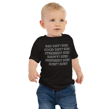 "Bad Day? Surf. Good Day? Surf. Stressed? Surf. Happy? Surf. Inspired? Surf. Surf? Surf!" printed on a black baby jersey short sleeve tee worn by a male