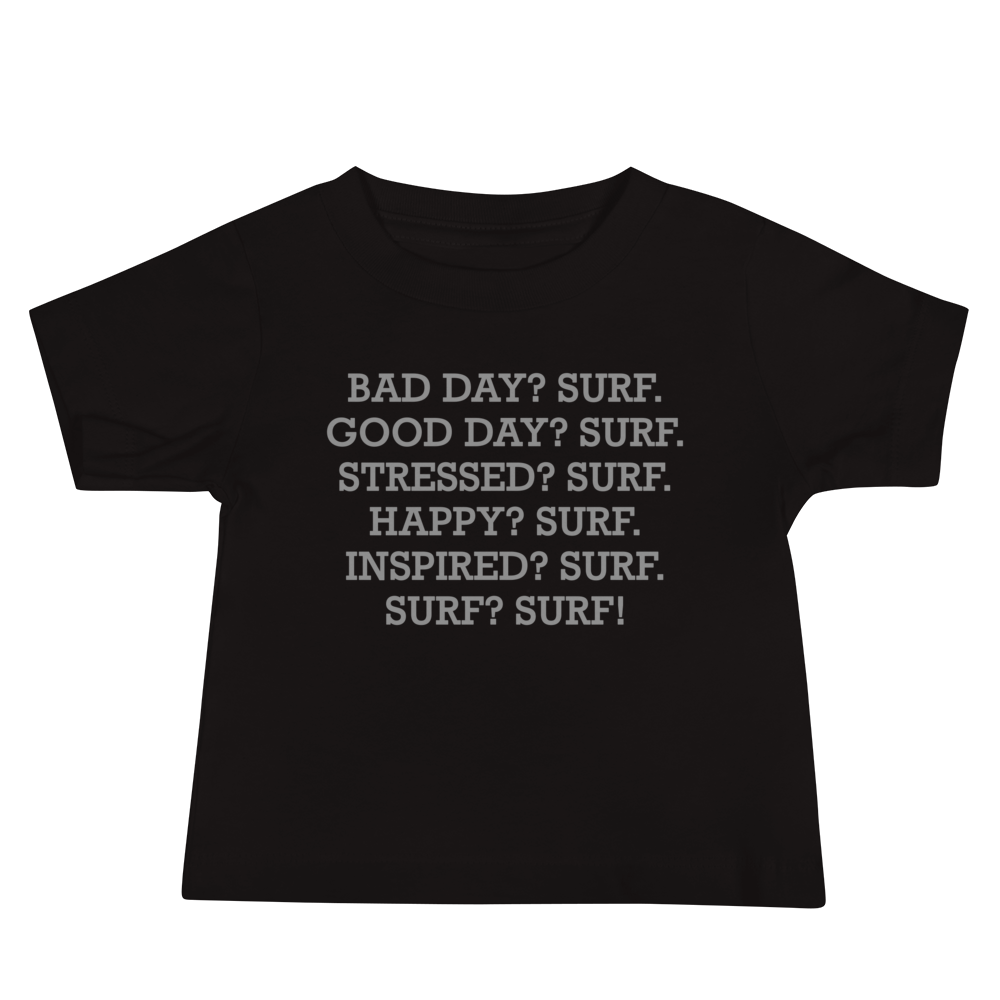 "Bad Day? Surf. Good Day? Surf. Stressed? Surf. Happy? Surf. Inspired? Surf. Surf? Surf!" printed on a black baby jersey short sleeve tee laying on a flat surface