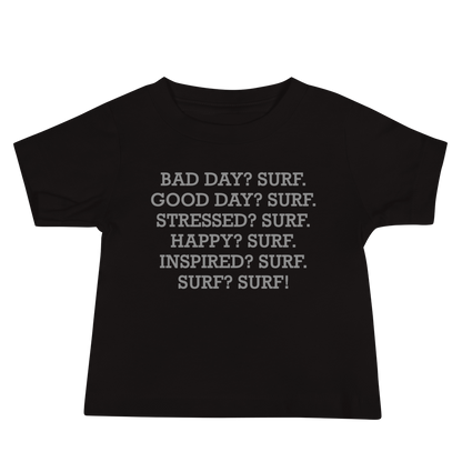 "Bad Day? Surf. Good Day? Surf. Stressed? Surf. Happy? Surf. Inspired? Surf. Surf? Surf!" printed on a black baby jersey short sleeve tee laying on a flat surface