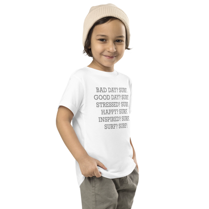 "Bad Day? Surf. Good Day? Surf. Stressed? Surf. Happy? Surf. Inspired? Surf. Surf? Surf!" printed on a white toddler short sleeve tee worn by a male who is also wearing a knit cap