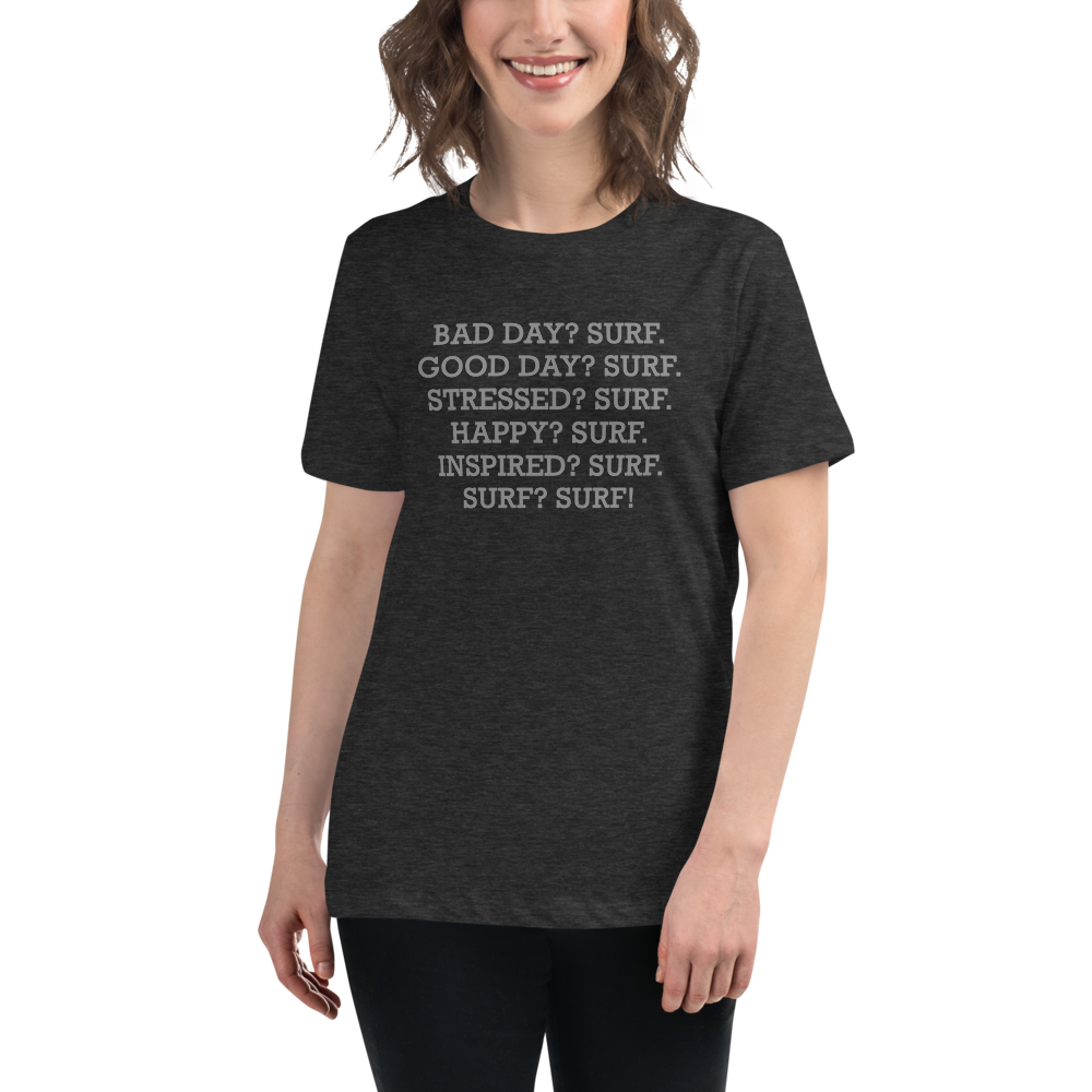 "Bad Day? Surf. Good Day? Surf. Stressed? Surf. Happy? Surf. Inspired? Surf. Surf? Surf!" printed on a dark grey heather women's relaxed t-shirt worn by a female