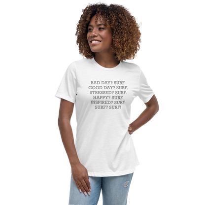 "Bad Day? Surf. Good Day? Surf. Stressed? Surf. Happy? Surf. Inspired? Surf. Surf? Surf!" printed on a white women's relaxed t-shirt worn by a female