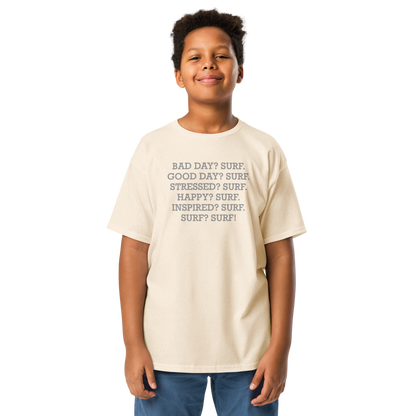 "Bad Day? Surf. Good Day? Surf. Stressed? Surf. Happy? Surf. Inspired? Surf. Surf? Surf!" printed on a natural youth classic tee worn by a male