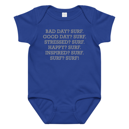 "Bad Day? Surf. Good Day? Surf. Stressed? Surf. Happy? Surf. Inspired? Surf. Surf? Surf!" printed on a royal baby jersey bodysuit laying on a flat surface amongst other clothes