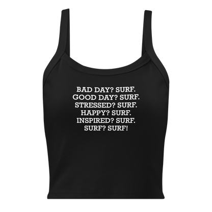 "Bad Day? Surf. Good Day? Surf. Stressed? Surf. Happy? Surf. Inspired? Surf. Surf? Surf!" printed on a solid black blend women's micro-rib tanktop laying on a flat surface