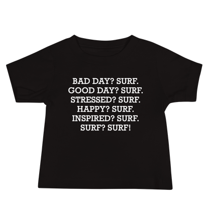 "Bad Day? Surf. Good Day? Surf. Stressed? Surf. Happy? Surf. Inspired? Surf. Surf? Surf!" printed on a black baby jersey short sleeve tee laying on a flat surface