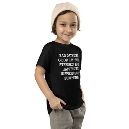 "Bad Day? Surf. Good Day? Surf. Stressed? Surf. Happy? Surf. Inspired? Surf. Surf? Surf!" printed on a black toddler short sleeve tee worn by a male who is also wearing a knit cap
