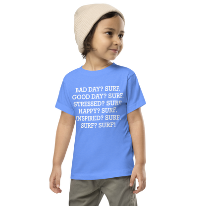 "Bad Day? Surf. Good Day? Surf. Stressed? Surf. Happy? Surf. Inspired? Surf. Surf? Surf!" printed on a heather columbia blue toddler short sleeve tee worn by a male wearing a cap