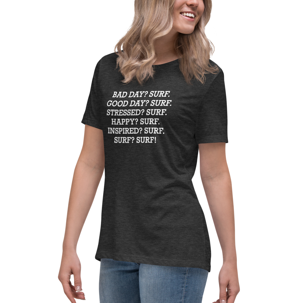 "Bad Day? Surf. Good Day? Surf. Stressed? Surf. Happy? Surf. Inspired? Surf. Surf? Surf!" printed on a dark grey heather women's relaxed t-shirt worn by a female