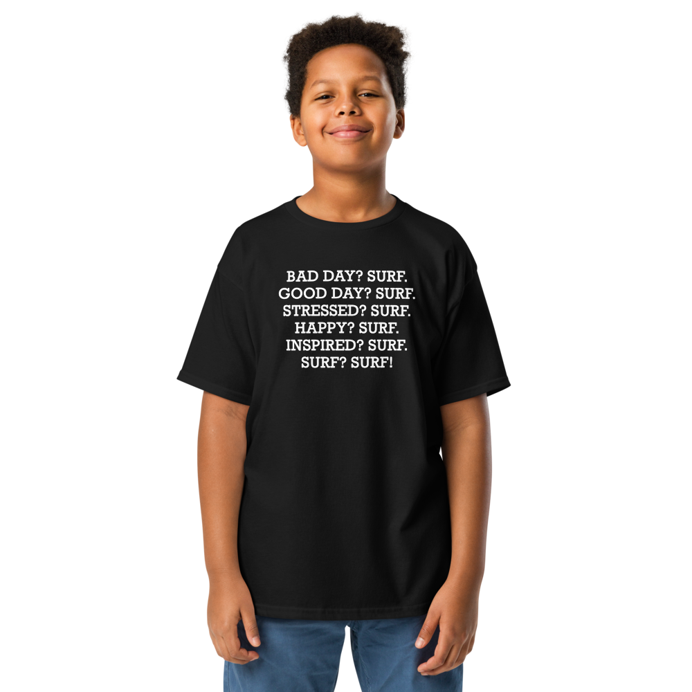 "Bad Day? Surf. Good Day? Surf. Stressed? Surf. Happy? Surf. Inspired? Surf. Surf? Surf!" printed on a black youth classic tee worn by a male