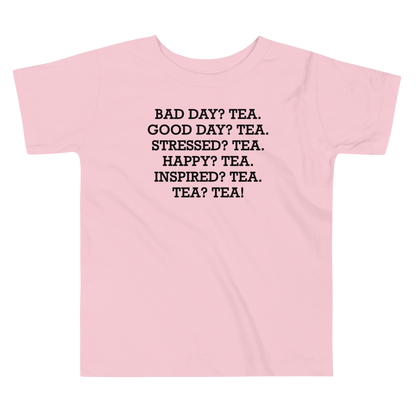 "Bad Day? Tea. Good Day? Tea. Stressed? Tea. Happy? Tea. Inspired? Tea. Tea? Tea!" printed on a pink toddler short sleeve tee laying on a flat surface