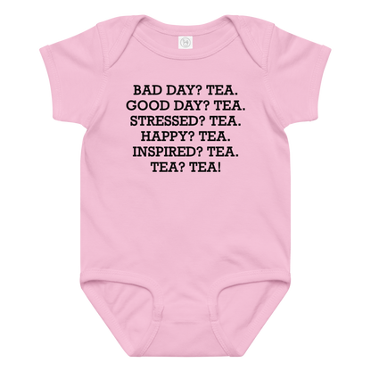 "Bad Day? Tea. Good Day? Tea. Stressed? Tea. Happy? Tea. Inspired? Tea. Tea? Tea!" printed on a pink baby jersey bodysuit laying on a flat surface amongst other clothes