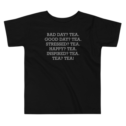 "Bad Day? Tea. Good Day? Tea. Stressed? Tea. Happy? Tea. Inspired? Tea. Tea? Tea!" printed on a black toddler short sleeve tee laying on a flat surface