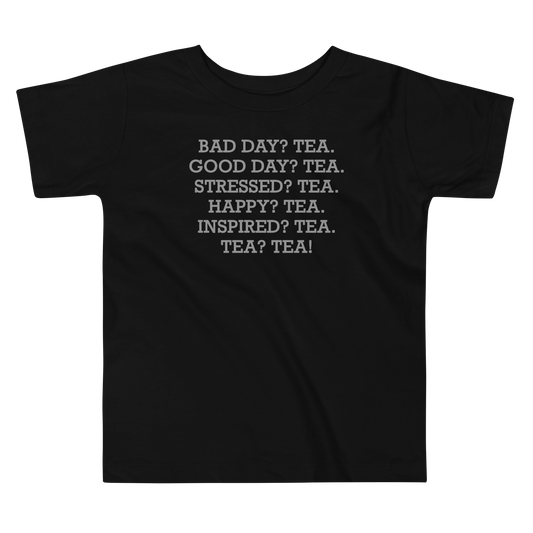"Bad Day? Tea. Good Day? Tea. Stressed? Tea. Happy? Tea. Inspired? Tea. Tea? Tea!" printed on a black toddler short sleeve tee laying on a flat surface