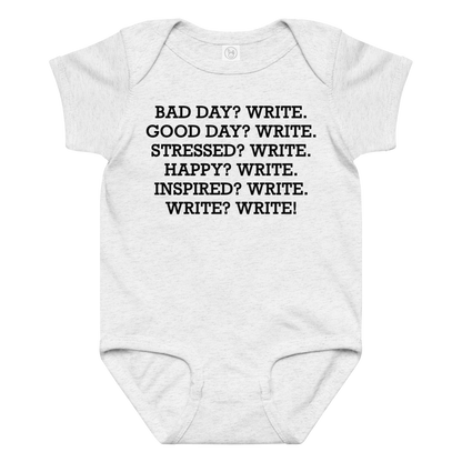 "Bad Day? Write. Good Day? Write. Stressed? Write. Happy? Write. Inspired? Write. Write? Write!" printed on a ash baby jersey bodysuit laying on a flat surface amongst other clothes
