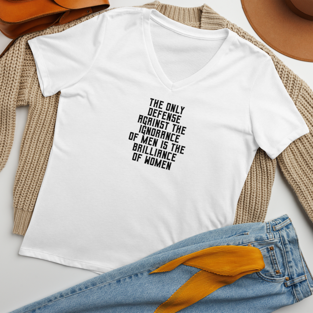 "The Only defense against the ignorance of men is the brilliance of women" printed on a solid white blend women's relaxed v-neck t-shirt laying on a flat surface amongst other clothes